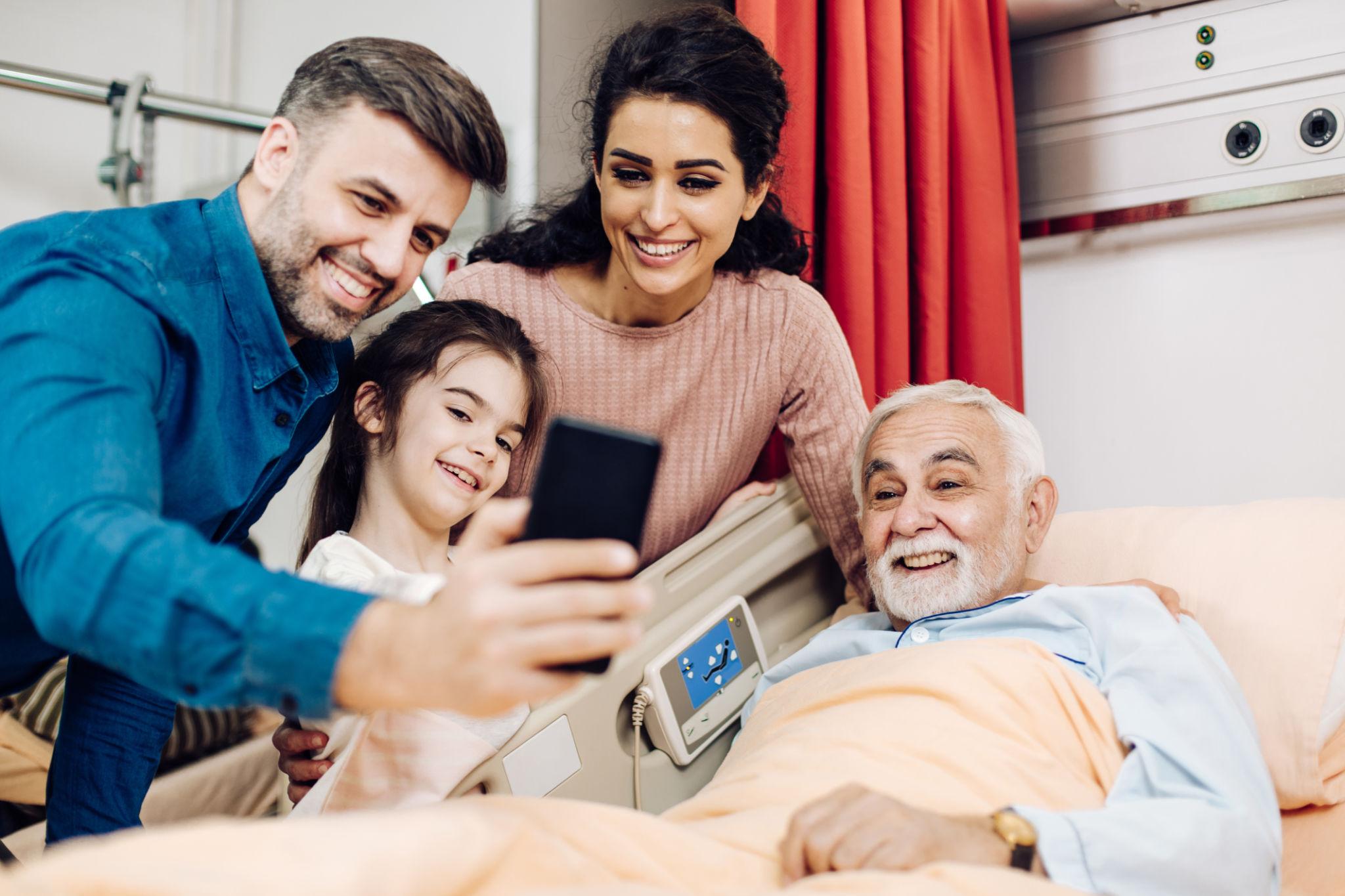 Family taking a selfie with a patient in hospital bed for prostate cancer awareness.